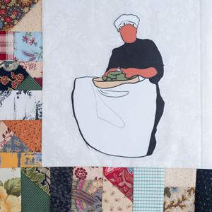 An African American woman holding a tray of food in her apron.
